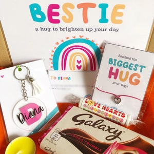 May include: A gift box with a variety of items, including a keychain with the name "Diana", a chocolate bar, a bracelet, and a candle. The box also contains a card with the text "Sending my BESTIE a hug to brighten up your day".