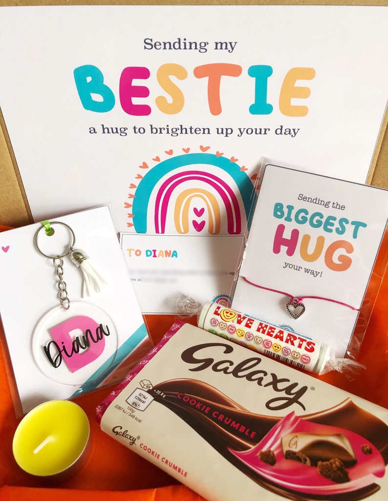 May include: A gift box with a variety of items, including a keychain with the name "Diana", a chocolate bar, a bracelet, and a candle. The box also contains a card with the text "Sending my BESTIE a hug to brighten up your day".
