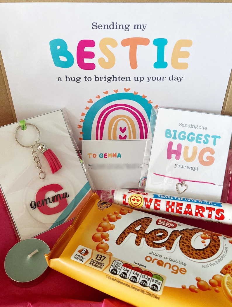 May include: A gift box with a variety of items. Includes a keychain with a pink tassel and the name "Gemma", a chocolate bar, a bracelet, and cards with the phrases "Sending my BESTIE" and "Sending the BIGGEST HUG".
