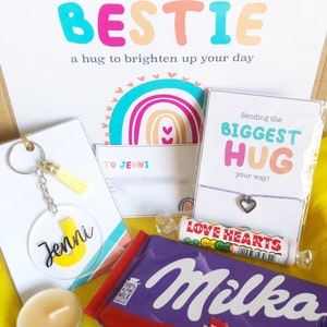 May include: A gift box with the text "Sending my BESTIE" and "a hug to brighten up your day." Includes a keychain, candle, bracelet, candy, and a Milka chocolate bar. The keychain has the name "Jenni" on it.