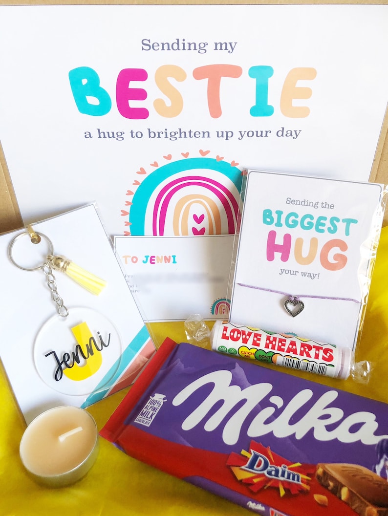 May include: A gift box with the text "Sending my BESTIE" and "a hug to brighten up your day." Includes a keychain, candle, bracelet, candy, and a Milka chocolate bar. The keychain has the name "Jenni" on it.