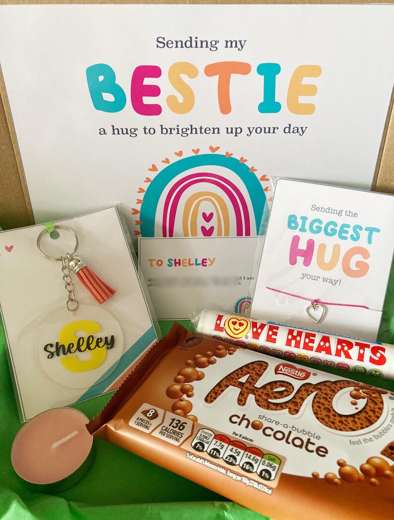 May include: A gift box with a card that says "Sending my BESTIE a hug to brighten up your day." Includes a keychain, a bracelet, a chocolate bar, a candle, and a candy roll. The keychain has a tassel and the name "Shelley".