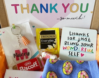 Può includere: Una scatola regalo contenente un portachiavi con il nome Macey, una bustina di tè Twinings, un biscotto Lotus Biscoff, un piccolo rotolo di caramelle, un biglietto con scritto thanks for just being your wonderful self e calzini blu con motivo a ciambelle.