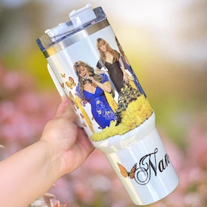 May include: White stainless steel tumbler with a colorful image of a group of women singing. The tumbler has a lid and a handle. The bottom of the tumbler has a butterfly design and the name "Nan" written in cursive.