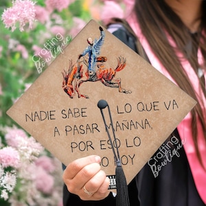 Op de afbeelding: Een afstudeerhoed met een bruine achtergrond en een zwarte kwast. De hoed heeft een tekening van een cowboy die een paard berijdt en de tekst "NADIE SABE LO QUE VA A PASAR MAÑANA, POR ESO LO HAGO HOY".