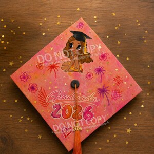 May include: A graduation cap with a vibrant pink and orange watercolor design. It features a cartoon illustration of a graduate, palm trees, and floral accents. The cap is adorned with the text "Graduada 2026" and a tassel.