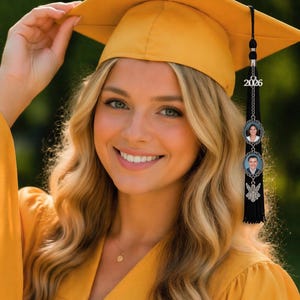 May include: A smiling person wearing a yellow graduation cap and gown. The cap has a black tassel with a 2026 charm and two photo charms. The gown is a matching yellow color. The image is taken outdoors.