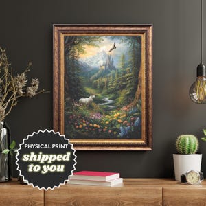 Puede incluir: Impresión artística enmarcada que representa una serena escena de bosque con un ciervo blanco, un castillo y un río. La obra de arte presenta colores vibrantes y un paisaje detallado, enmarcado en un marco dorado y ornamentado. La impresión se exhibe sobre una superficie de madera.