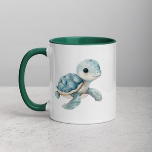 Puede incluir: Una taza de cerámica blanca con un borde verde presenta una ilustración de acuarela de una tortuga marina azul con un caparazón azul claro. La tortuga camina hacia la derecha.