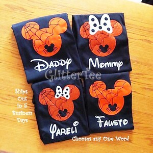 May include: Four black t-shirts with a spiderweb Mickey Mouse design. The shirts have the words "Daddy", "Mommy", "FAUSTO", and "PARELI" printed on them.