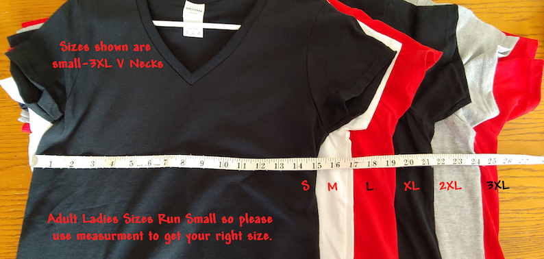 May include: A stack of five V-neck t-shirts in different sizes, from small to 3XL. The shirts are black, white, red, grey, and heather grey. A measuring tape is laid across the bottom of the shirts, with the corresponding sizes marked. The text "Sizes shown are small-3XL V Necks" is written in red at the top of the image. The text "Adult Ladies Sizes Run Small so please use measurement to get your right size." is written in red at the bottom of the image.