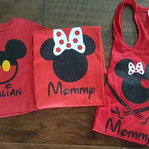 May include: Red shirts with a black and white Mickey Mouse and Minnie Mouse design. The shirts say "Julian" and "Mommy". A red tank top with a black and white Minnie Mouse design says "Mommy" with a glittery finish.