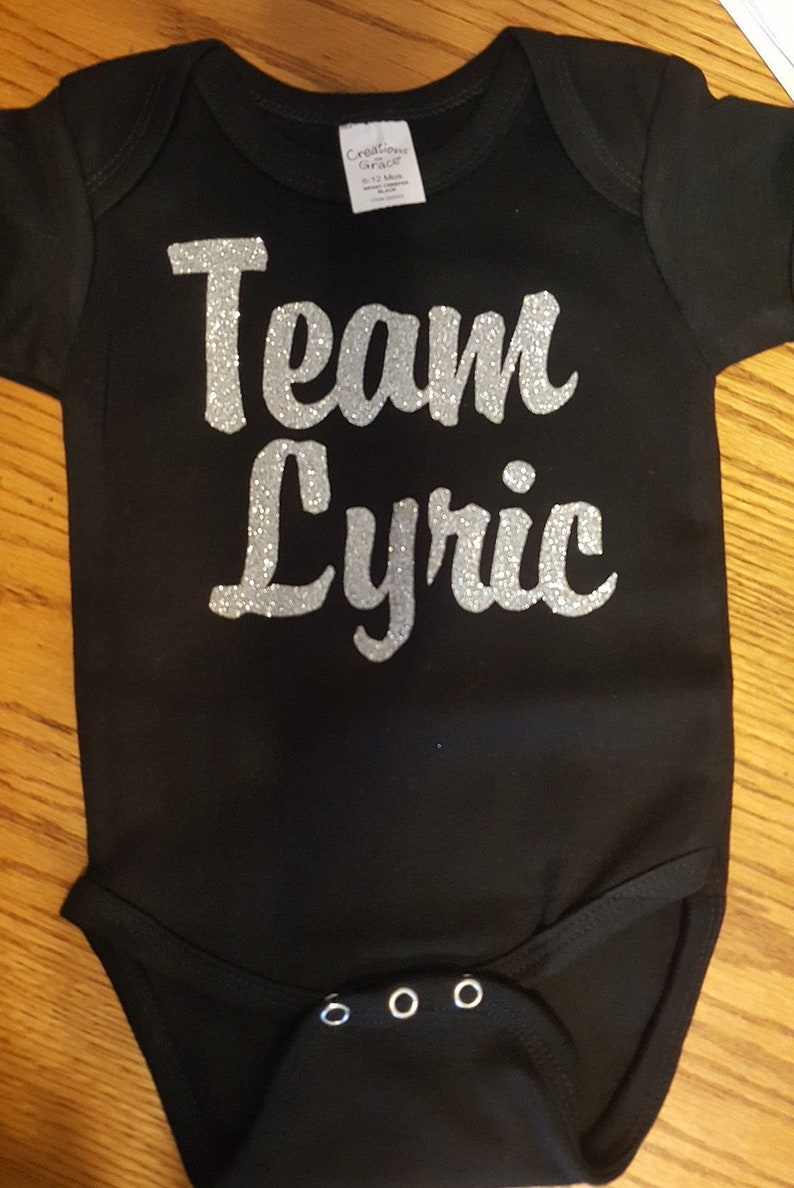May include: Black bodysuit with silver glitter lettering that reads "Team Lyric".