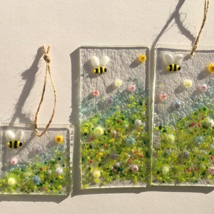 May include: Three glass panels featuring a floral design and a bee. The panels are of varying sizes and are hung with twine.