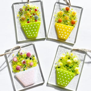 May include: Four glass flower pot ornaments with white polka dots. The pots are filled with colorful glass flowers. The ornaments are hanging from twine.