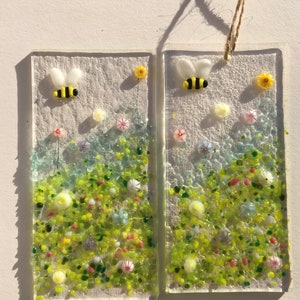 May include: Two rectangular glass panels with a white background and a green, yellow, and white floral design.  Each panel features a small yellow and black bee.
