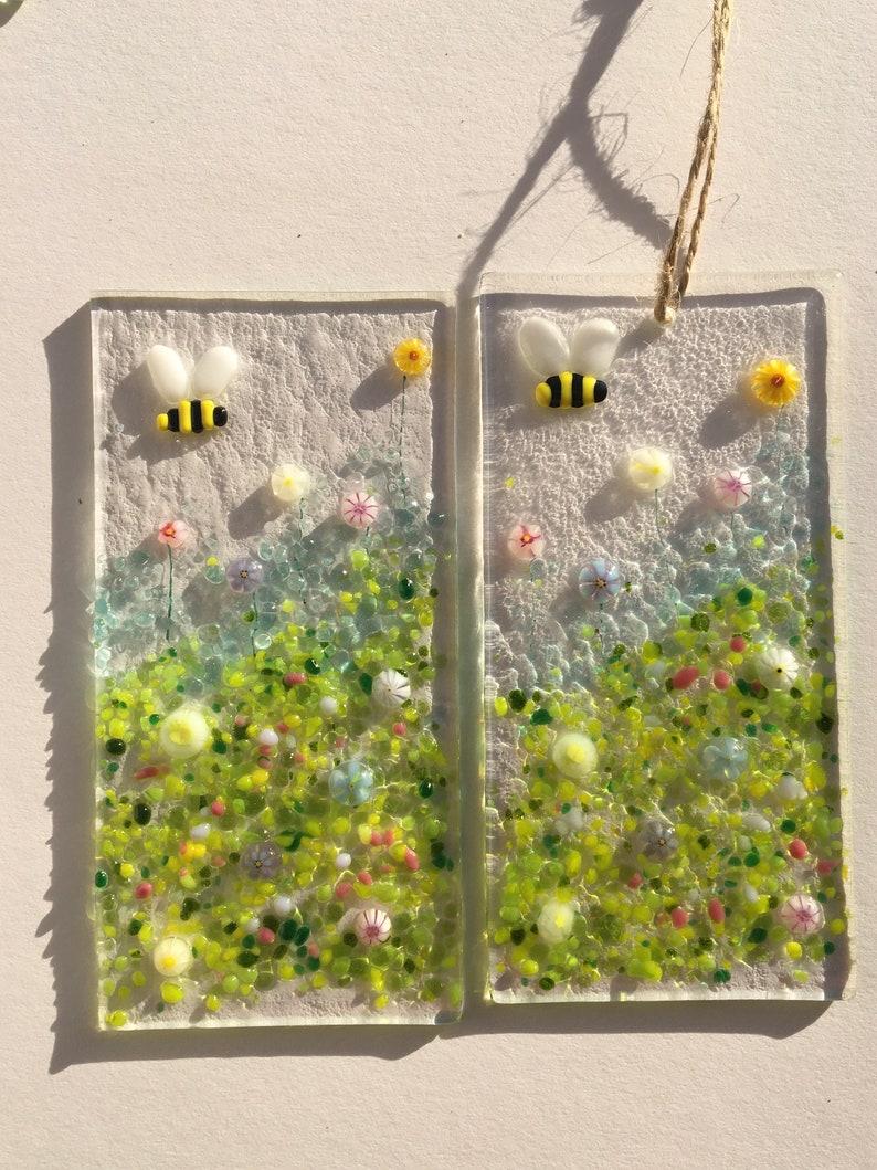 May include: Two rectangular glass panels with a white background and a green, yellow, and white floral design.  Each panel features a small yellow and black bee.