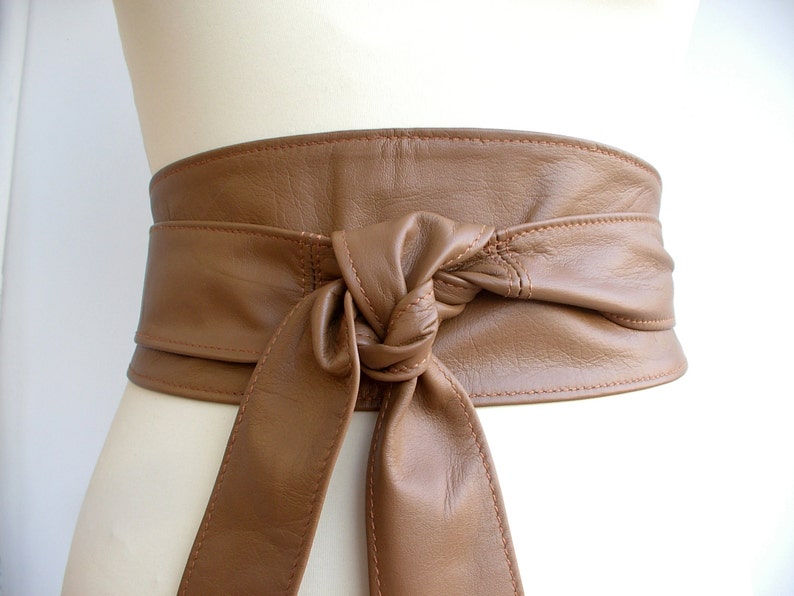 a tan leather obi belt tied around the waist of a mannequin.