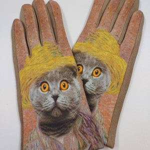 May include: A pair of brown suede gloves with a printed image of a grey cat wearing a yellow hat. The cat's eyes are orange.