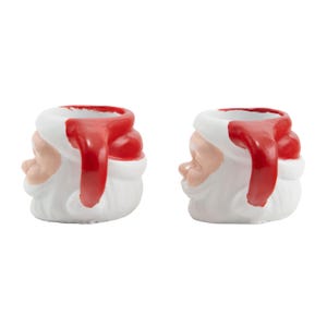 Puede incluir: Dos figuras de cer&aacute;mica de Pap&aacute; Noel. Cada figura es blanca con un gorro y ribete rojos, una cara rosada y una barba blanca. Las figuras de Pap&aacute; Noel est&aacute;n dise&ntilde;adas para guardar objetos peque&ntilde;os o servir como piezas decorativas.