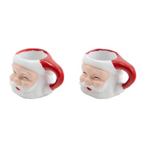 Puede incluir: Dos tazas de cer&aacute;mica de Pap&aacute; Noel. Cada taza es blanca con un asa y un gorro rojos, y presenta una cara sonriente de Pap&aacute; Noel con mejillas rosadas y barba blanca. Para la temporada navide&ntilde;a.