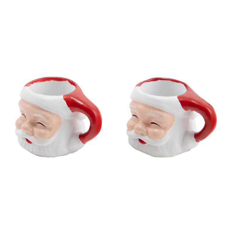 Puede incluir: Dos tazas de cer&aacute;mica de Pap&aacute; Noel. Cada taza es blanca con un asa y un gorro rojos, y presenta una cara sonriente de Pap&aacute; Noel con mejillas rosadas y barba blanca. Para la temporada navide&ntilde;a.