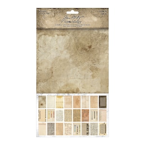 May include: A pack of 24 double-sided paper sheets for crafting. The pack features a distressed, vintage aesthetic with a brown background and a variety of printed designs. The text on the front of the pack reads "Jim Holtz idea-ology" and "Backdrops Toiles de Fond".
