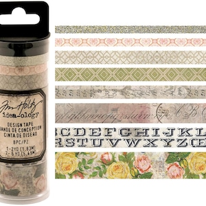 May include: A set of eight washi tapes in a clear plastic container. The tapes feature a variety of designs, including glitter, floral patterns, and alphabet letters. The container is labeled "Im Holz idea-ology Design Tape 8PC/PZ 1-2YD (1.83M) 7-6 YD (5.49M)"