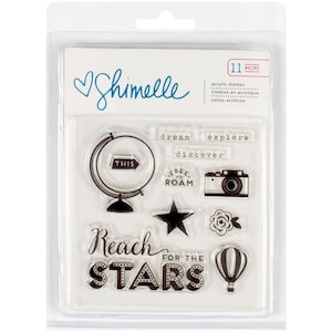 May include: A clear plastic package containing 11 clear acrylic stamps with travel-themed images and text. The text includes "Reach for the Stars", "Free to Roam", "This", "Dream", "Explore", and "Discover".