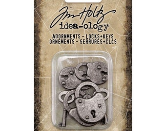 Puede incluir: Seis abalorios de metal de color plateado en forma de candados y llaves. Los abalorios están empaquetados en una tarjeta con el texto "Pim Holtz idea-ology Adornments - Locks + Keys Ornements - Serrures + Clés 6 Pieces/6 Pièces".
