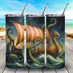 May include: Three stainless steel insulated tumblers with lids and straws. Each tumbler features a Viking ship design with a sea monster and a stormy sea. The ships have orange and white striped sails. The background is a beach scene.