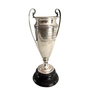 May include: A silver-toned trophy cup with two curved handles, resting on a round black base. The cup features an engraved inscription reading: CHAPTER 88, St. Louis, MO, MARY FRANCES WALKER, HONOR STUDENT, Shawnee High School, 1927.