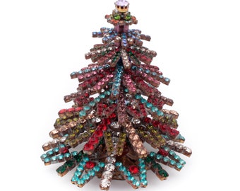 May include: A small, colorful Christmas tree ornament made of rhinestones. The tree is decorated with red, pink, blue, green, and clear rhinestones.