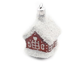 May include: A red and white Christmas ornament shaped like a house with a snowy roof. The house has a heart and windows on the front.