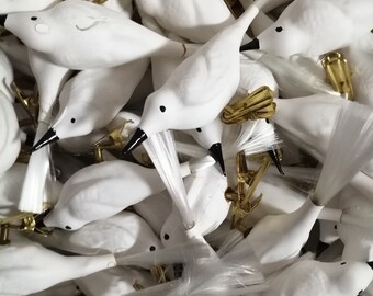 Può includere: Un mucchio di figurine di uccelli bianche con code in fibra ottica. Gli uccelli hanno occhi neri e sono attaccati a clip dorate.