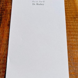 May include: A blank white sheet of paper with the text "From the Desk Of Dr. Rockey" printed at the top.