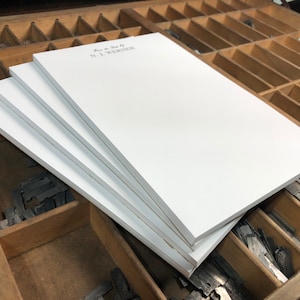 May include: A stack of four white notepads with the text "From the Desk Of N.J. WEAVER" printed on the top notepad.
