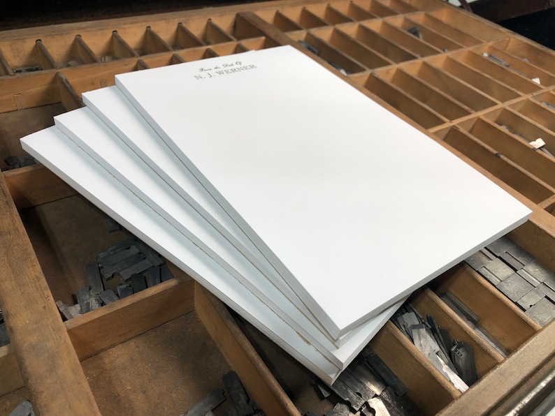 May include: A stack of four white notepads with the text "From the Desk Of N.J. WEAVER" printed on the top notepad.