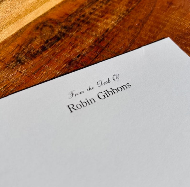 May include: A white card with the text "From the Desk of Robin Gibbons" printed in black ink.
