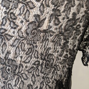 May include: Black lace fabric with a floral pattern. The lace is delicate and intricate, with a fine mesh background.