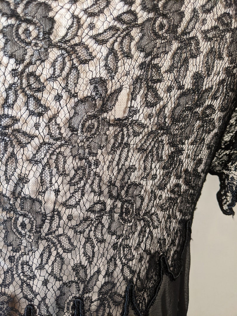 May include: Black lace fabric with a floral pattern. The lace is delicate and intricate, with a fine mesh background.