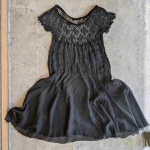 May include: A black lace and chiffon dress with a scalloped neckline and a flowing skirt.