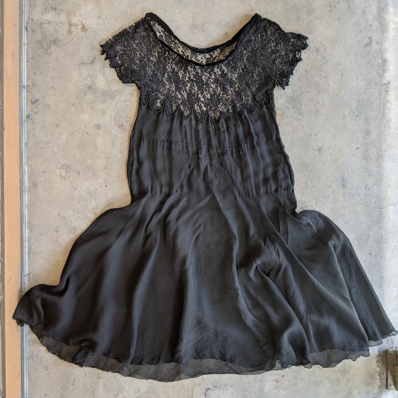 May include: A black lace and chiffon dress with a scalloped neckline and a flowing skirt.