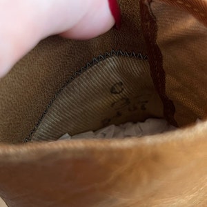 K&ouml;nnte beinhalten: Nahaufnahme des Innenraums eines braunen Lederstiefels. Der Stiefel ist mit braunem Stoff gef&uuml;ttert und hat ein schwarzes N&auml;hdetail am oberen Rand.