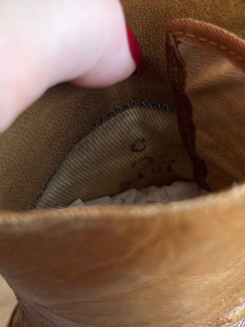 K&ouml;nnte beinhalten: Nahaufnahme des Innenraums eines braunen Lederstiefels. Der Stiefel ist mit braunem Stoff gef&uuml;ttert und hat ein schwarzes N&auml;hdetail am oberen Rand.