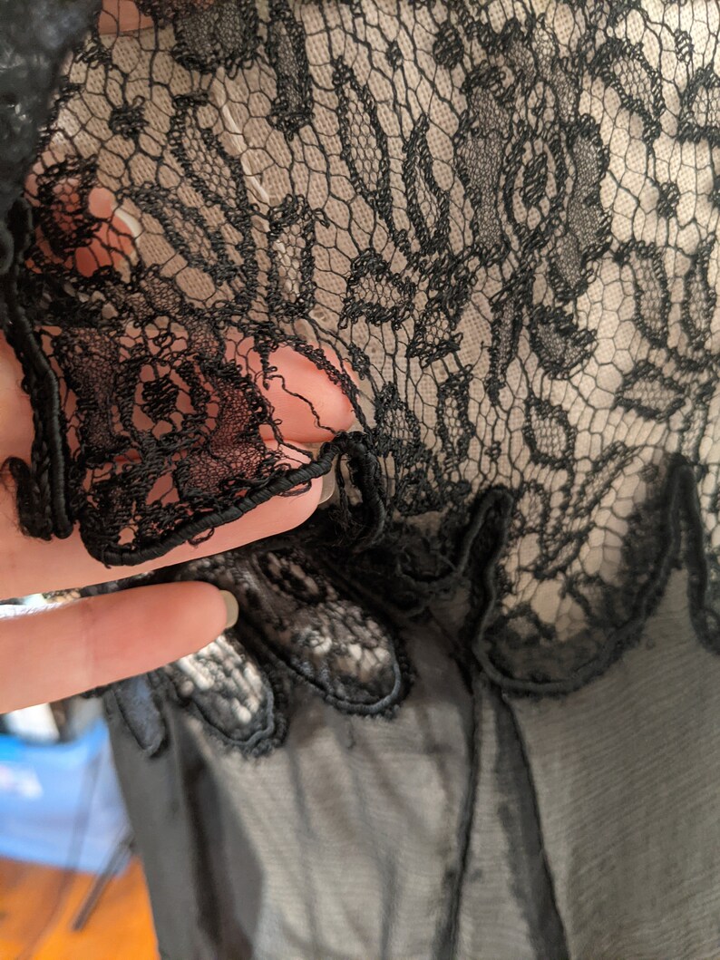 May include: Black lace fabric with a delicate floral pattern. The lace is sheer and has a soft, flowing texture.