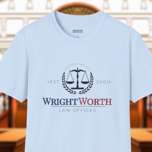 May include: Light blue t-shirt featuring the WrightWorth Law Offices logo. The logo includes a scale of justice within a laurel wreath, the text "Justice for All", and the establishment year "2001".