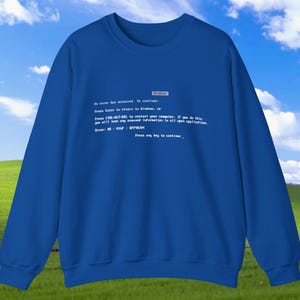 May include: A royal blue sweatshirt featuring the text of a Windows error message in white. The text includes the phrase "An error has occurred" and instructions for restarting the computer. The sweatshirt has a crew neck and long sleeves.