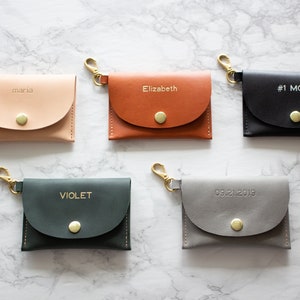 May include: Five small leather keychains with gold clasps and a snap closure. The keychains are personalized with the names "Maria", "Elizabeth", "#1 MOM", "VIOLET", and the date "09.21.2019".