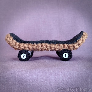 May include: A small crocheted skateboard with brown and black yarn. The skateboard has two black wheels with white centers.